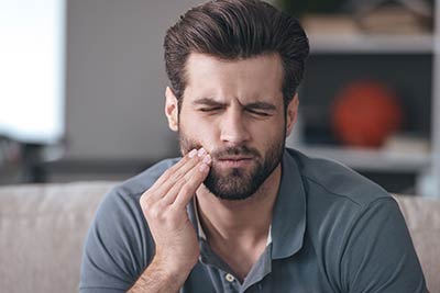 man holding his mouth in need of an emergency dentist